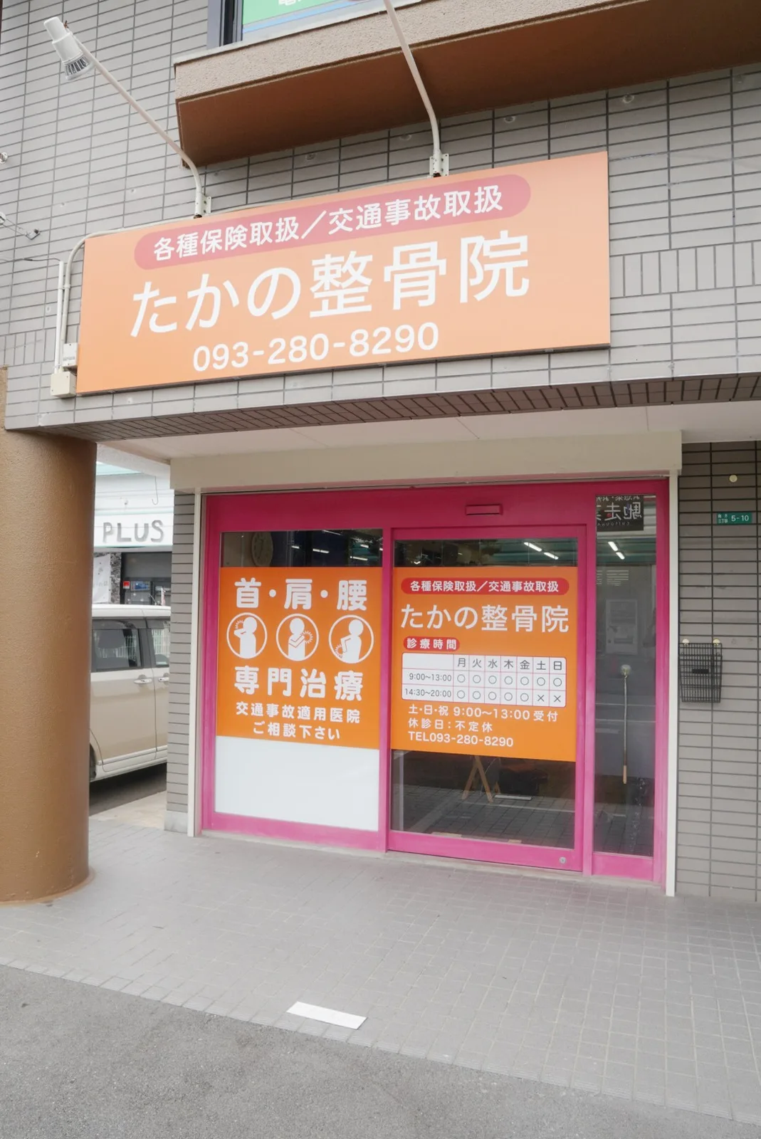 たかの整骨院の外観。オレンジ色の看板とピンク色の入口がある建物1階の店舗